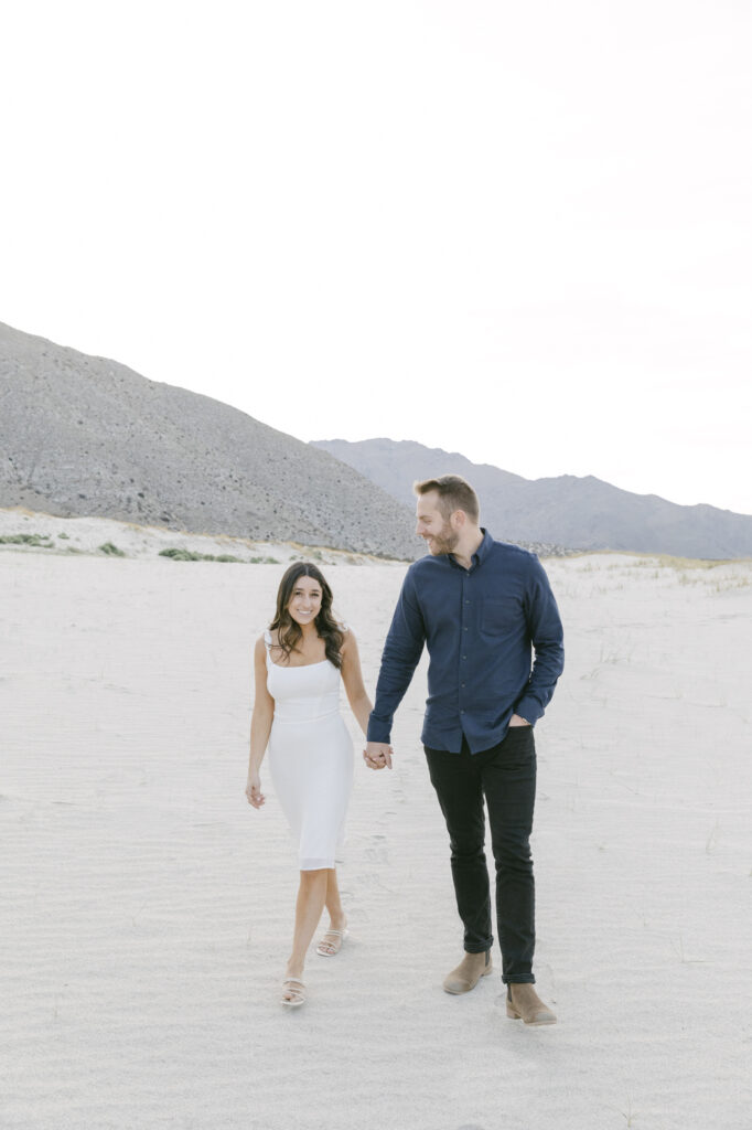 couple walking holding hands during their engagement session in palm springs