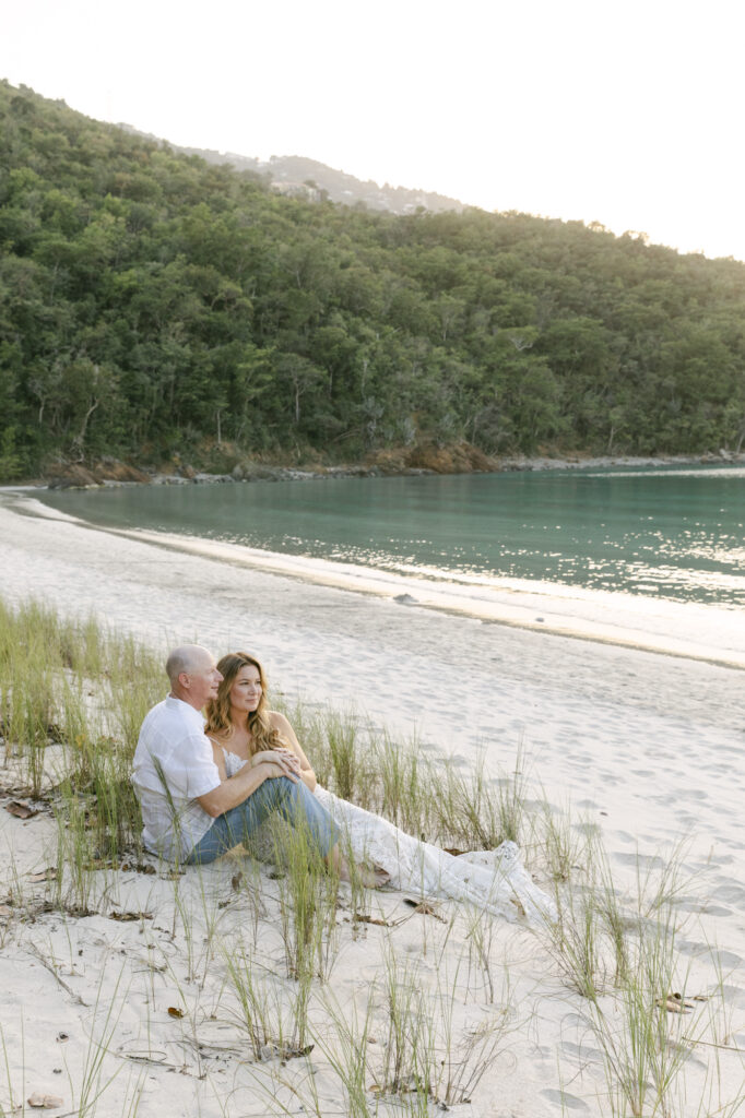 couple sitting on beach during engagement photos at magens bay