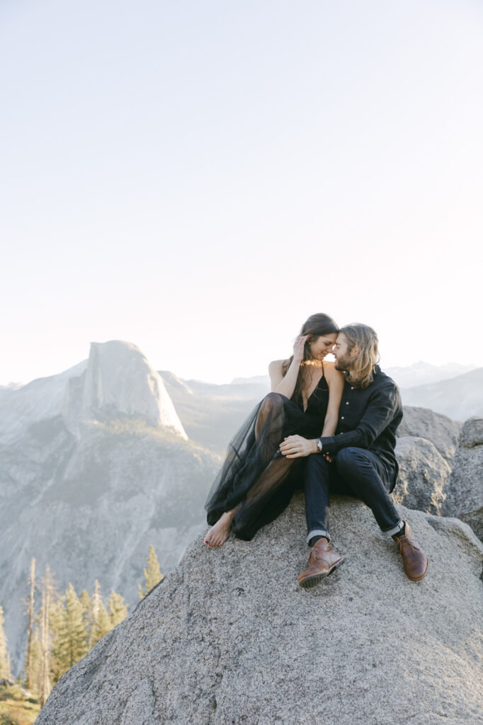 couple sitting mountainside with each other during engagement photos at yosemite national park 