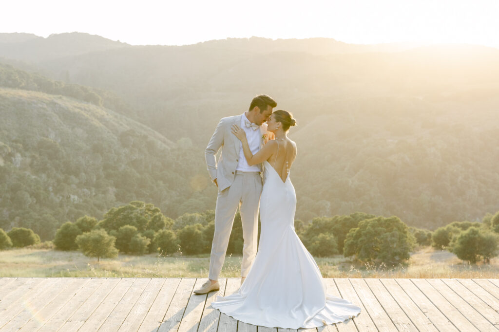 bride and groom holding onto each other during sunset photos in carmel