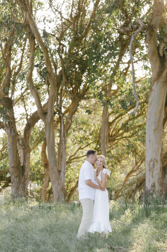 couple embracing under eucalyptus trees during a Natural Bridges State Beach engagement session in Santa Cruz California