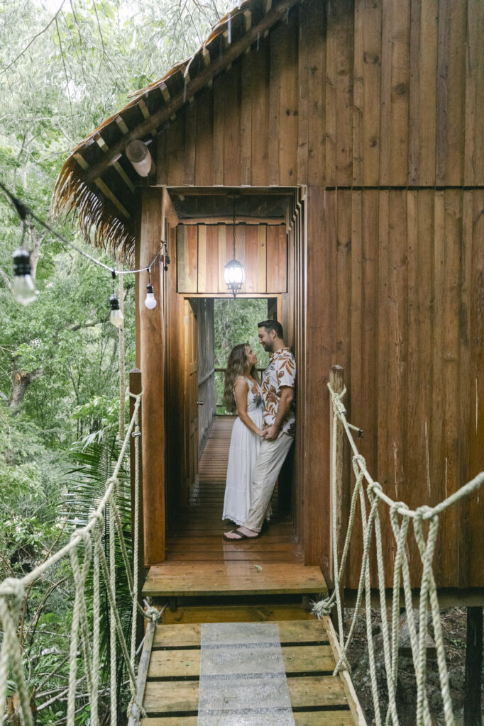Bride and groom kissing in the doorway of a jungle treehouse strung with cafe lights, Belize destination wedding photographer Paulina Perrucci