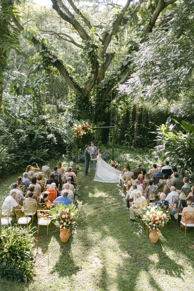 Tropical garden wedding ceremony beneath a sprawling jungle tree with terracotta urns and tropical florals, Belize destination wedding photographer Paulina Perrucci