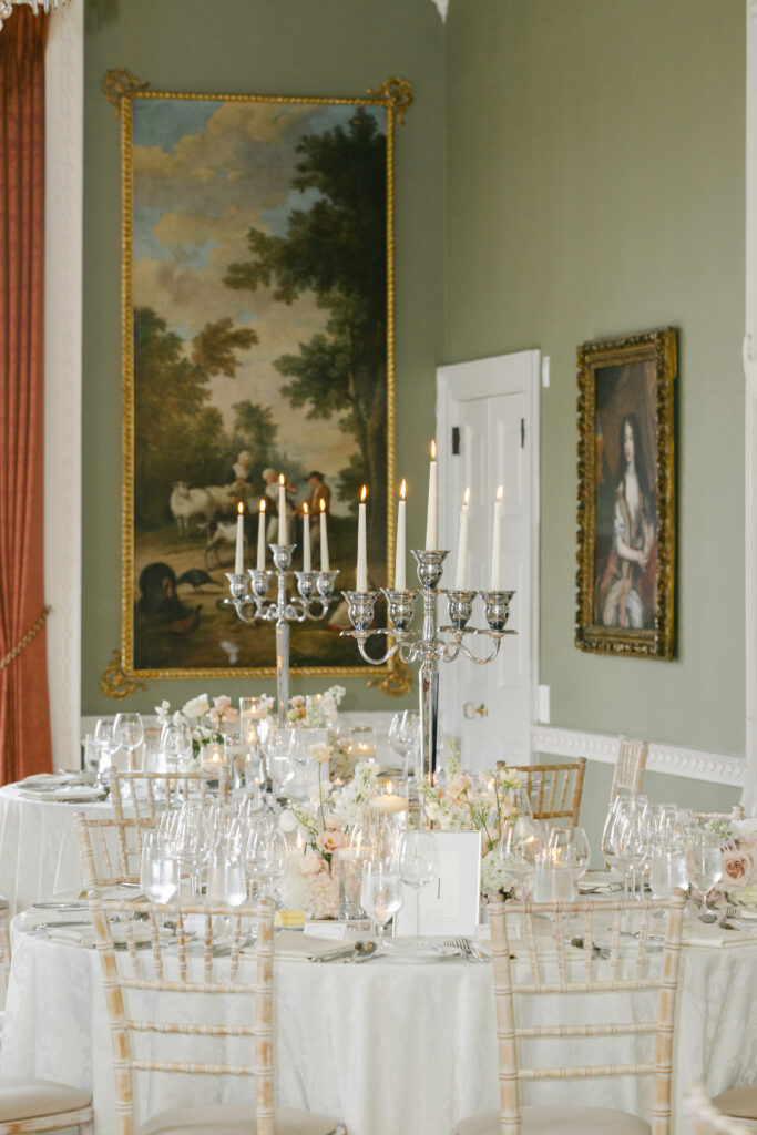 Reception tablescape at Luttrellstown Castle with candelabras, blush garden roses, and a gilded oil painting behind.