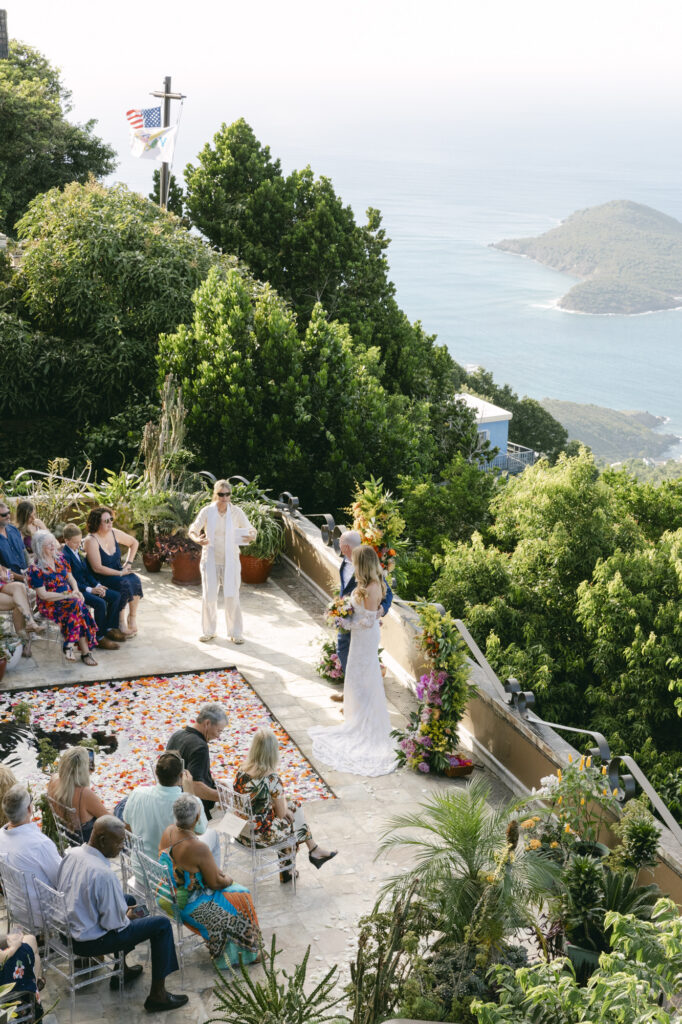 Clifftop wedding ceremony overlooking the Caribbean and outer islands in St. Thomas, with a tropical orange and yellow floral arch, US Virgin Islands destination wedding photographer Paulina Perrucci