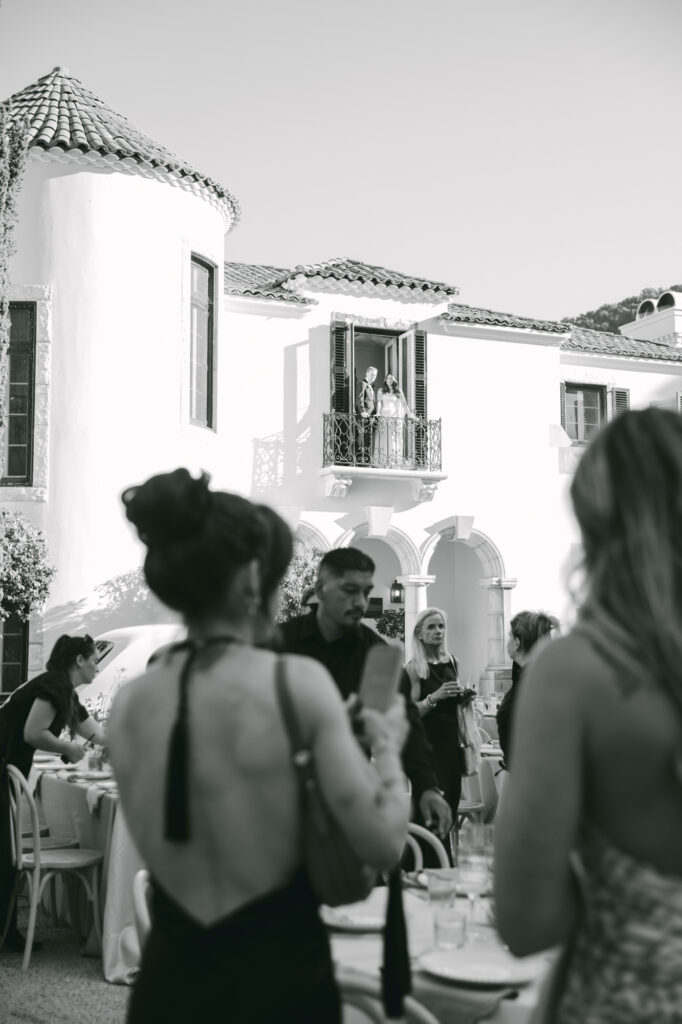 Black and white photo of wedding guests gathered near the exterior of Chateau Noel at Stonepine Estate in Carmel Valley