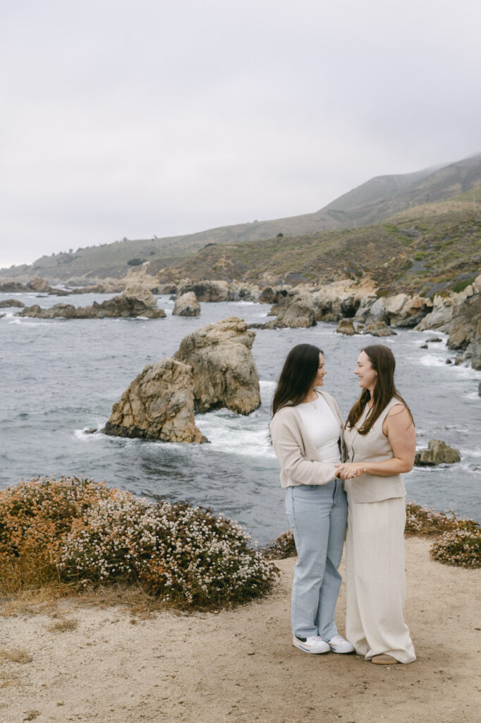 Engaged couple holding hands on rocky coastline at Garrapata State Park near Carmel