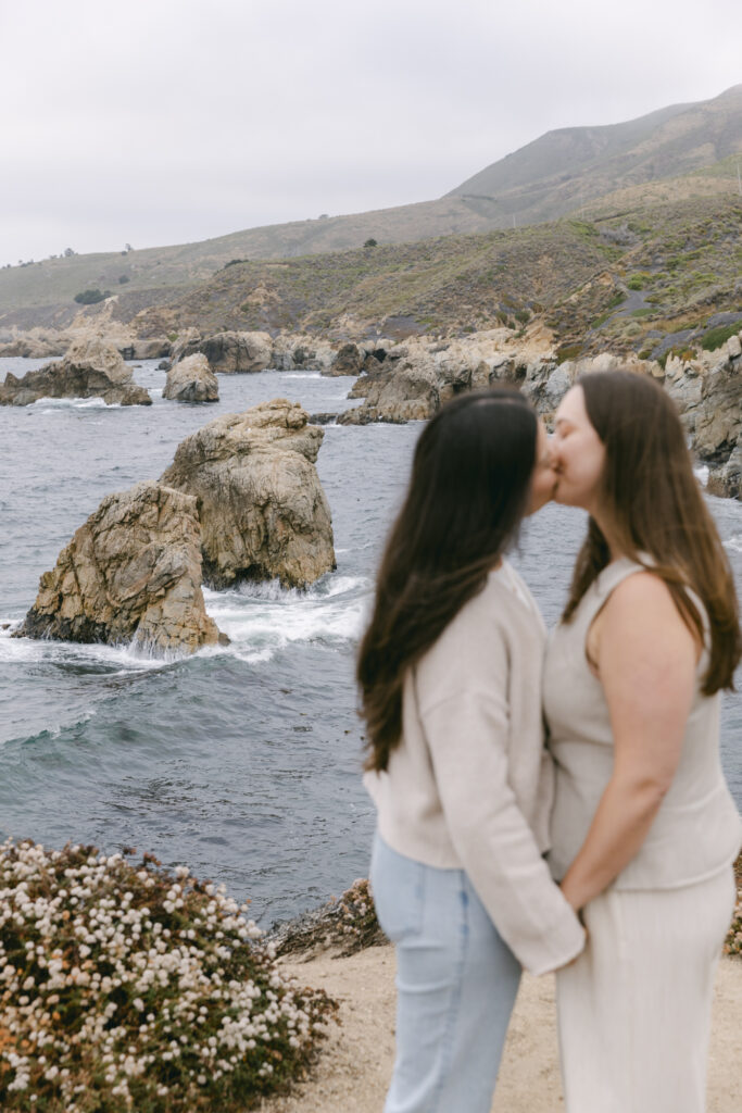 Engaged couple kissing on rocky coastline at Garrapata State Park in Carmel