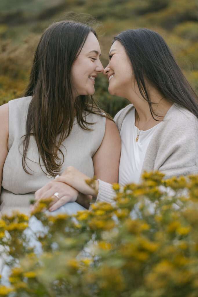Engaged couple nose to nose in yellow wildflowers at Garrapata State Park in Carmel