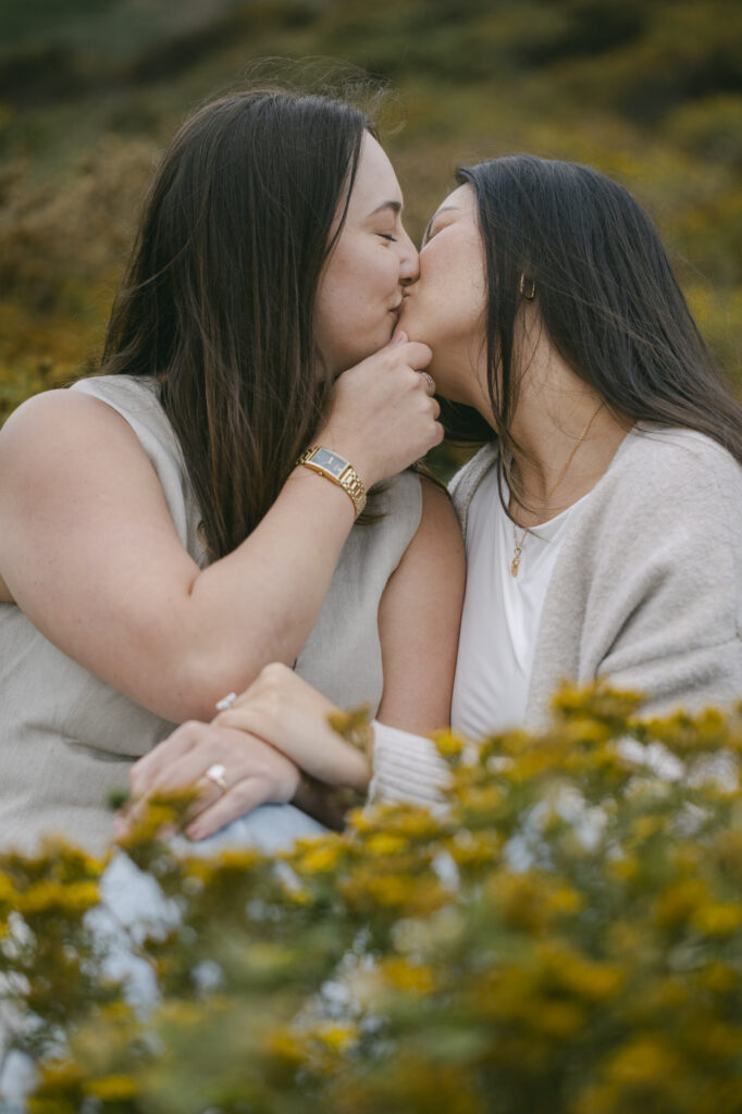 Newly engaged couple kissing among wildflowers at Garrapata State Park near Carmel