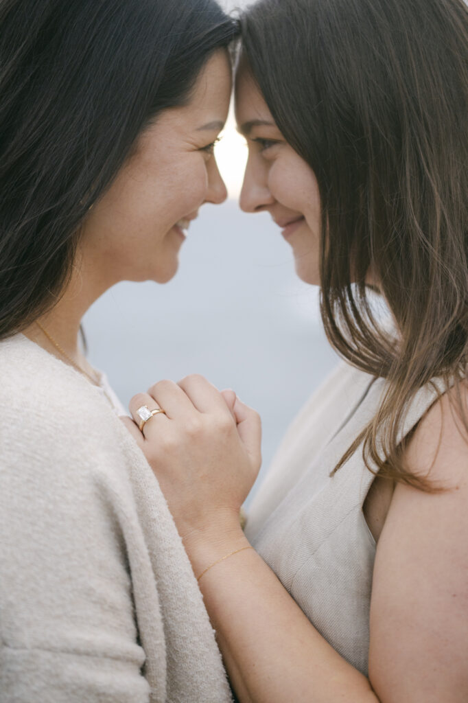 Close-up of engaged couple with engagement ring, foreheads together at Garrapata State Park near Carmel