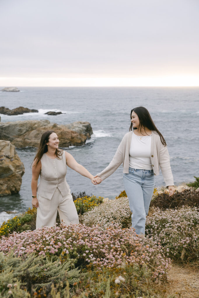 Engaged couple walking hand in hand along the coastline at Garrapata State Park